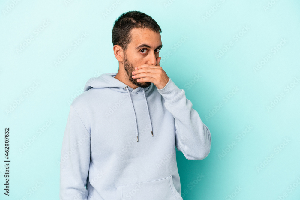 Young caucasian man isolated on blue background covering mouth with hands looking worried. Young caucasian man isolated on blue background covering mouth with hands looking worried.