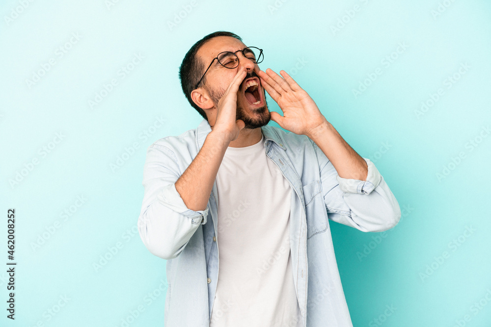 Young caucasian man isolated on blue background shouting excited to front.