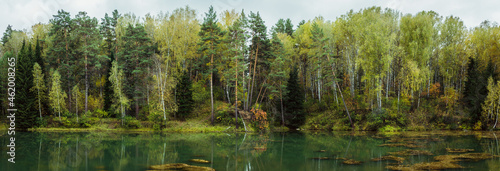 Panorama of autumn lake in the middle of forest. Panorama landscape.