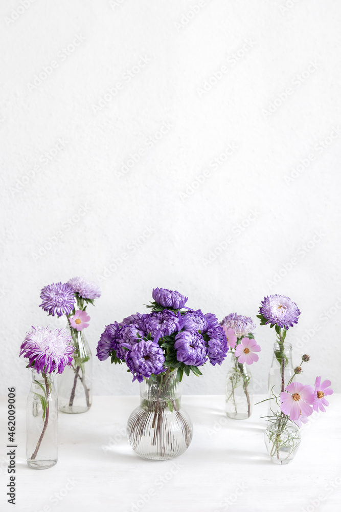 Glass vases with fresh chrysanthemum flowers on a blurred white background. Glass vases with fresh chrysanthemum flowers on a blurred white background.