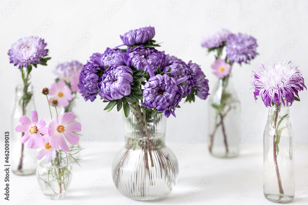 Glass vases with fresh chrysanthemum flowers on a blurred white background. Glass vases with fresh chrysanthemum flowers on a blurred white background.