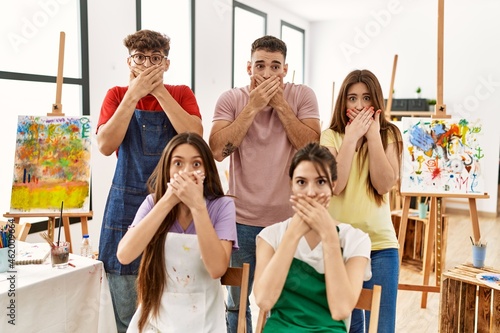Group of five hispanic artists at art studio shocked covering mouth with hands for mistake. secret concept.