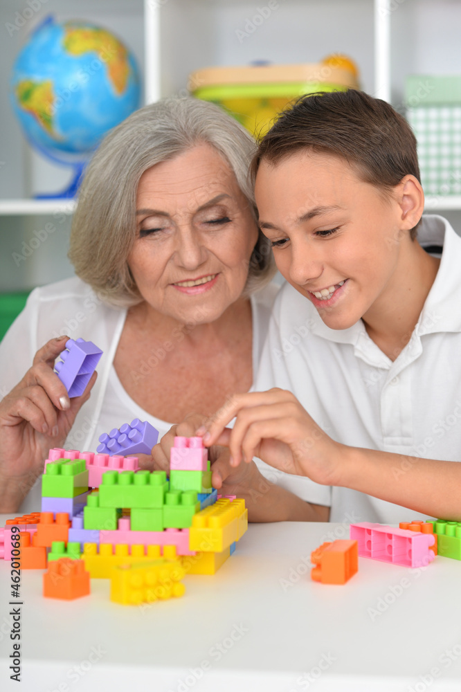 Smiling boy playing with colorful plastic blocks with grandmother Smiling boy playing with colorful plastic blocks with grandmother