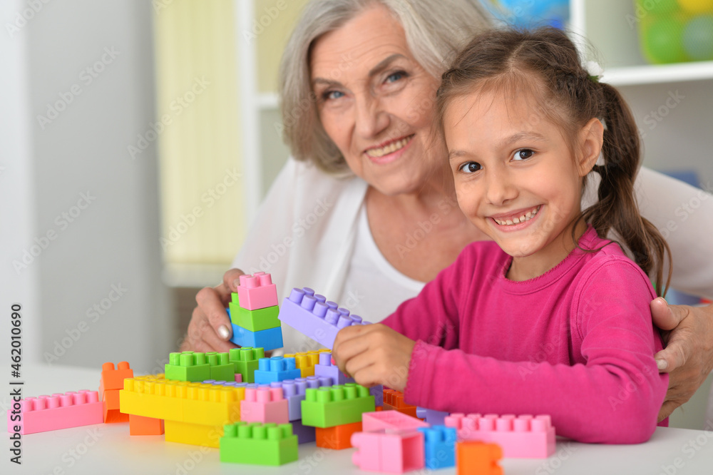 Cute girl and grandmother playing with colorful plastic blocks Cute girl and grandmother playing with colorful plastic blocks