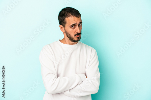 Young caucasian man isolated on blue background unhappy looking in camera with sarcastic expression.