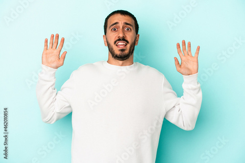 Young caucasian man isolated on blue background being shocked due to an imminent danger © Asier
