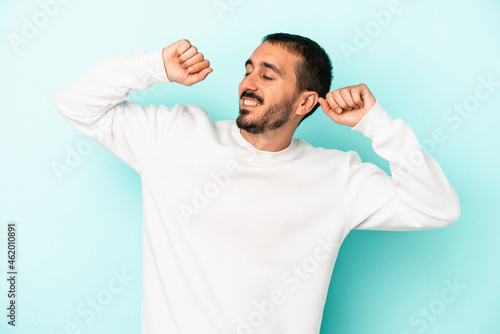 Young caucasian man isolated on blue background celebrating a special day, jumps and raise arms with energy.