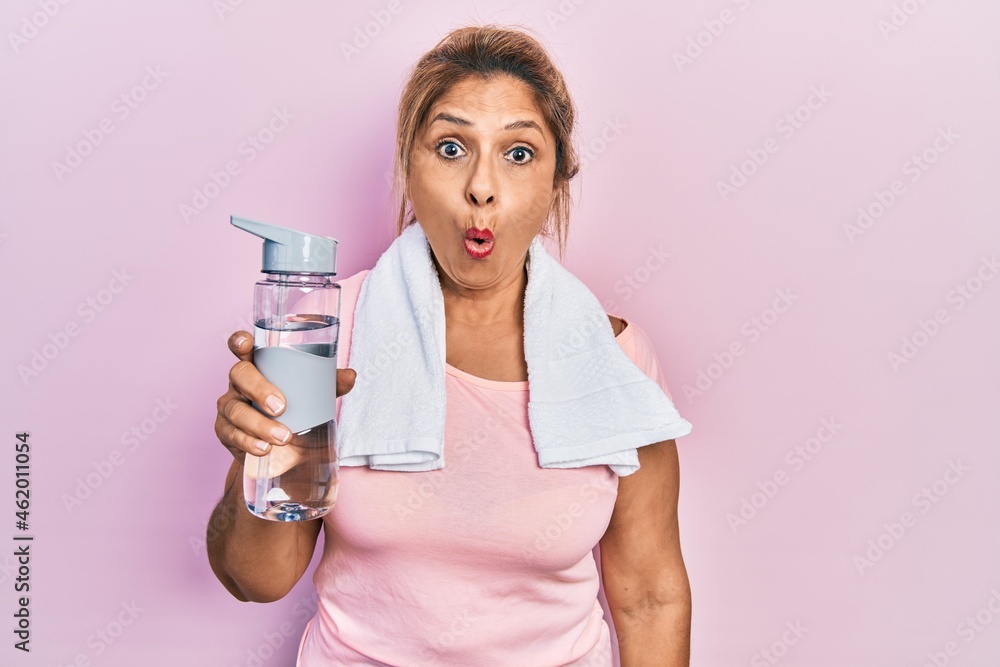 Middle age hispanic woman wearing sportswear holding water bottle scared and amazed with open mouth for surprise, disbelief face Middle age hispanic woman wearing sportswear holding water bottle scared and amazed with open mouth for surprise, disbelief face