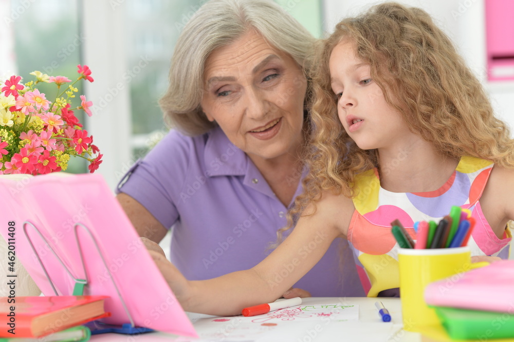 Portrait of grandmother and granddaughter drawing together Portrait of grandmother and granddaughter drawing together