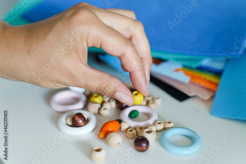 Close up on hands of unknown female designer working at the table - Hand of woman holding handcraft wood plastic rings and pearls choosing material for project - Creativity hobby and leisure concept