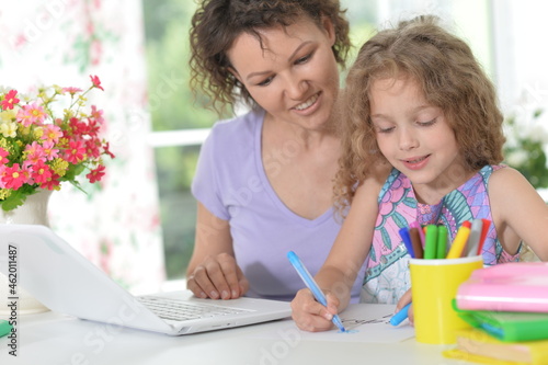 beautiful girl and her mother with a laptop at home drawing