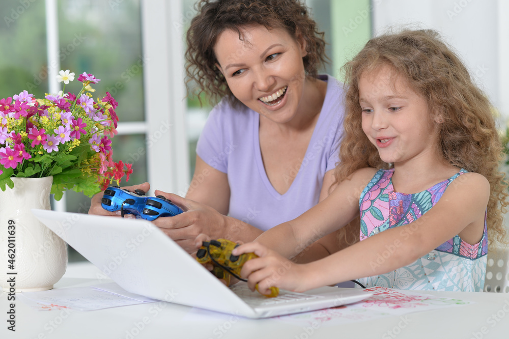 Mother and daughter using laptop playing video game Mother and daughter using laptop playing video game