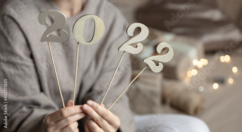 Christmas background with wooden numbers 2022 on sticks in female hands