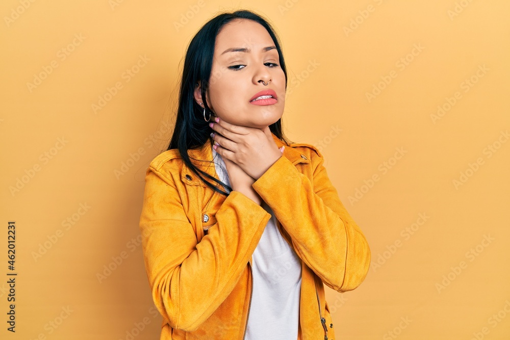 Beautiful hispanic woman with nose piercing wearing yellow leather jacket shouting suffocate because painful strangle. health problem. asphyxiate and suicide concept. Beautiful hispanic woman with nose piercing wearing yellow leather jacket shouting suffocate because painful strangle. health problem. asphyxiate and suicide concept.