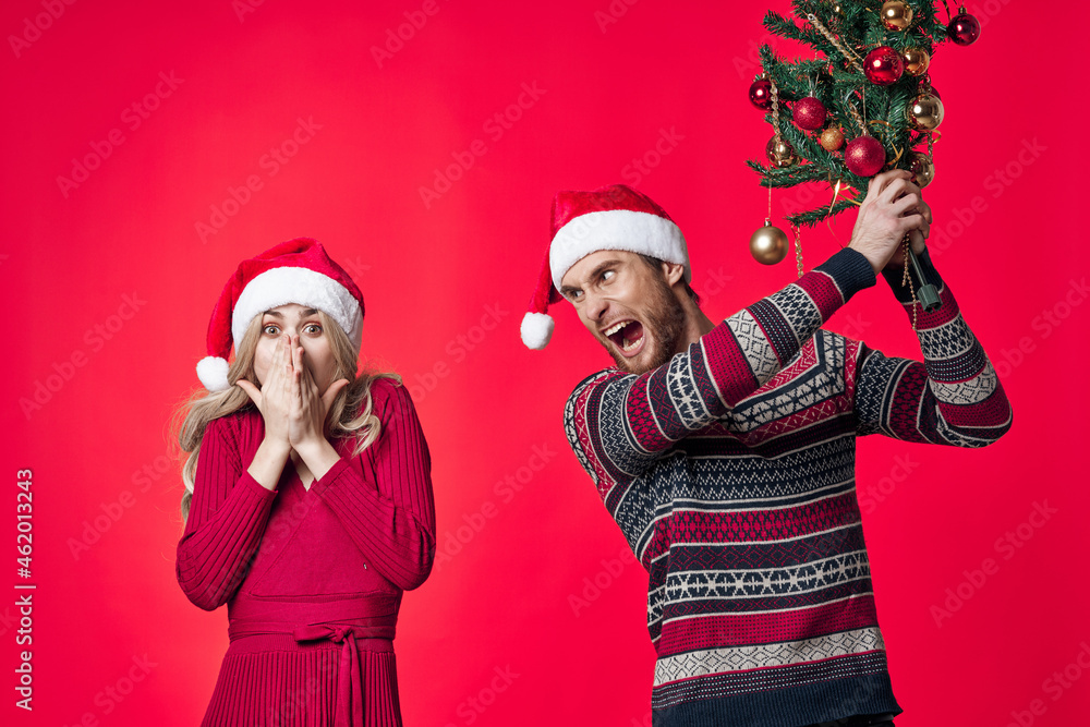 cheerful young couple in new year clothes decoration toys red background cheerful young couple in new year clothes decoration toys red background