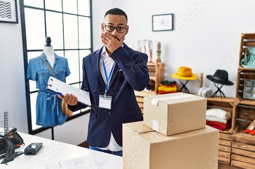 African american man working as manager at retail boutique shocked covering mouth with hands for mistake. secret concept. © Krakenimages.com