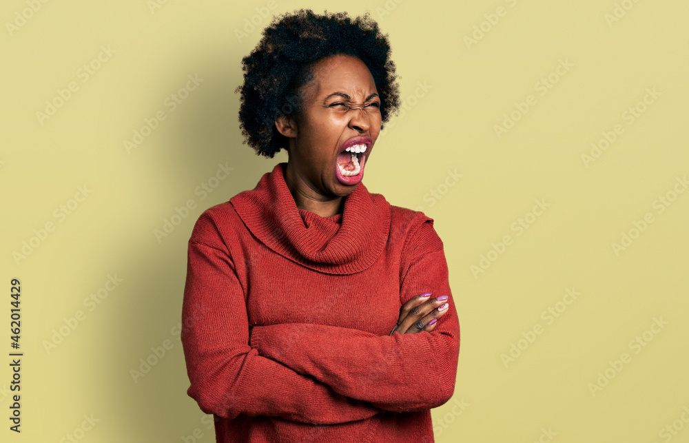 African american woman with afro hair with arms crossed gesture angry and mad screaming frustrated and furious, shouting with anger. rage and aggressive concept. African american woman with afro hair with arms crossed gesture angry and mad screaming frustrated and furious, shouting with anger. rage and aggressive concept.