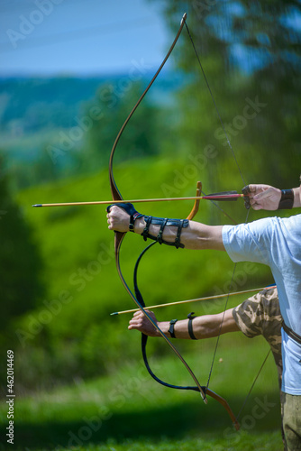 professional archers shooting with modern longbows at meadow