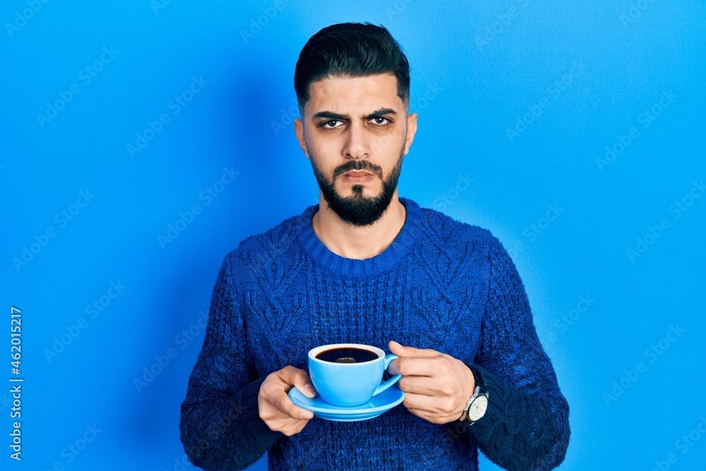Handsome man with beard drinking a cup of coffee skeptic and nervous, frowning upset because of problem. negative person. Handsome man with beard drinking a cup of coffee skeptic and nervous, frowning upset because of problem. negative person.