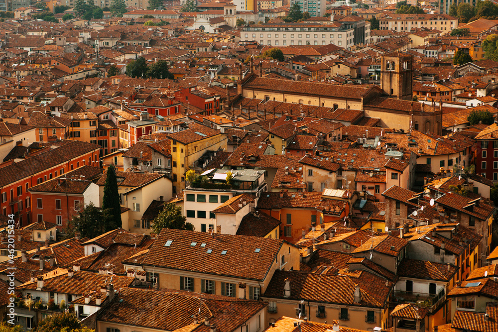 Aerial view of the historical center of Brescia (Lombardy, Italy) with red tile roofs, chimneys, cathedral's domes and tall white brick old towers. Traditional European medieval architecture.