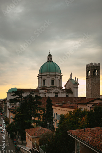 The turquoise dome with stone white sculptures and the tower of the central Catholic church (Duomo Vecchio Cathedral) at sunset in Brescia, Lombardy, Italy. Panoramic view. Italian architecture