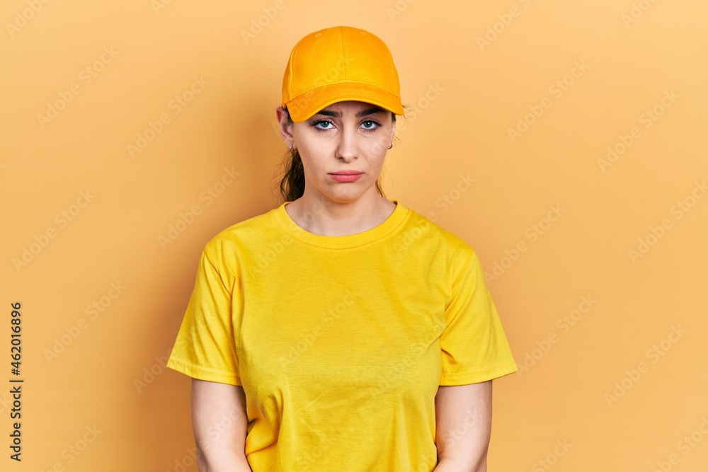 Young hispanic woman wearing delivery uniform and cap depressed and worry for distress, crying angry and afraid. sad expression.