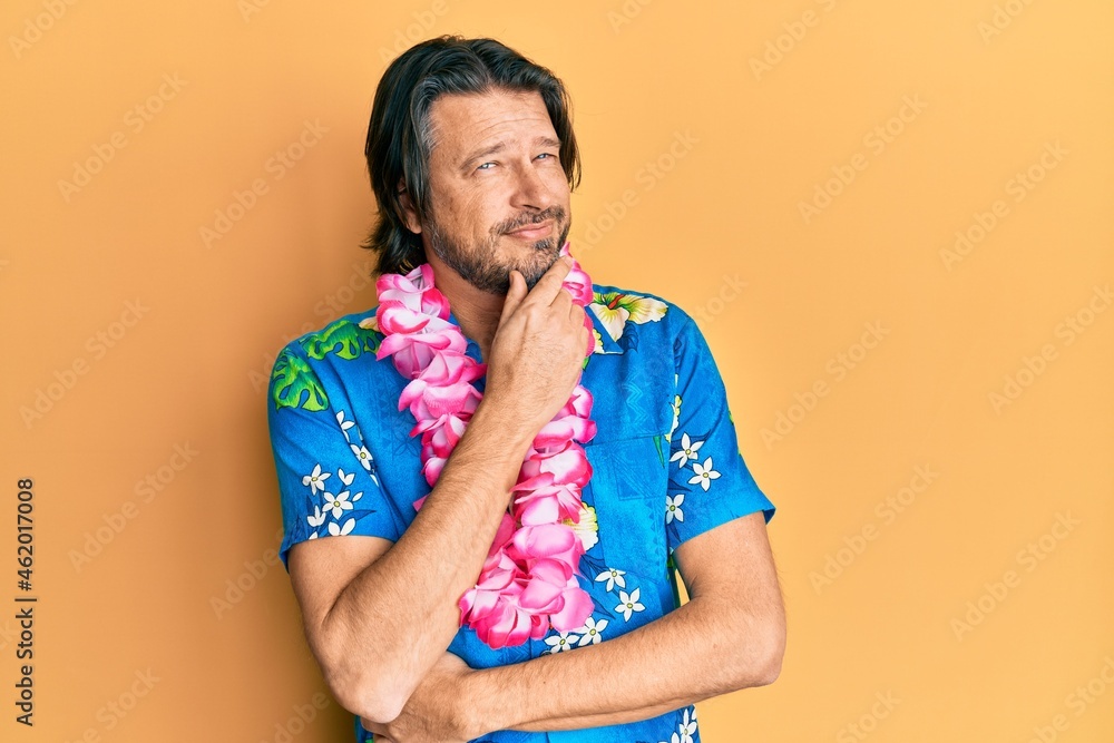 Middle age handsome man wearing summer shirt and hawaiian lei smiling looking confident at the camera with crossed arms and hand on chin. thinking positive. Middle age handsome man wearing summer shirt and hawaiian lei smiling looking confident at the camera with crossed arms and hand on chin. thinking positive.