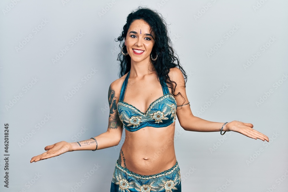 Young woman wearing bindi and traditional belly dance clothes smiling showing both hands open palms, presenting and advertising comparison and balance Young woman wearing bindi and traditional belly dance clothes smiling showing both hands open palms, presenting and advertising comparison and balance