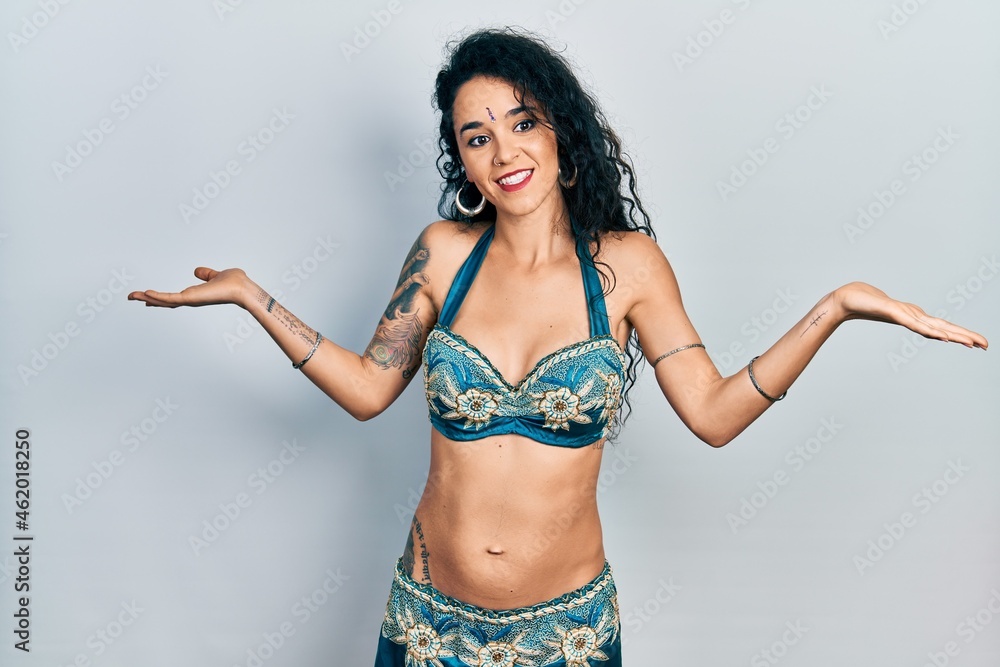 Young woman wearing bindi and traditional belly dance clothes clueless and confused expression with arms and hands raised. doubt concept. Young woman wearing bindi and traditional belly dance clothes clueless and confused expression with arms and hands raised. doubt concept.