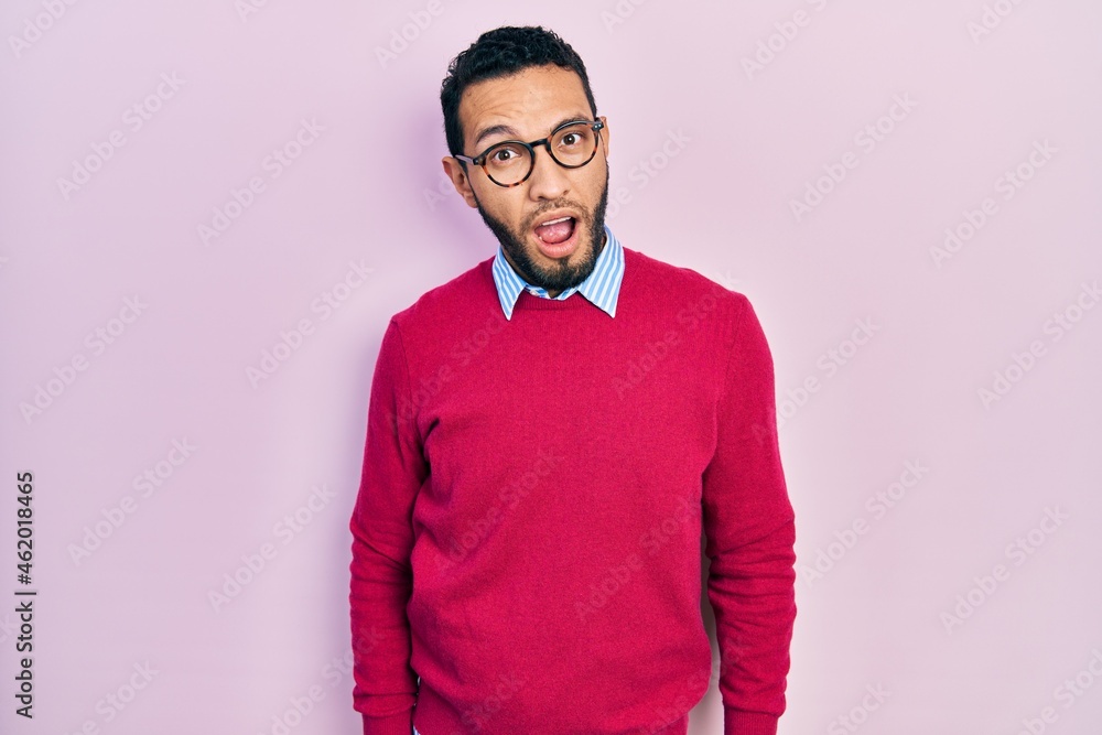 Hispanic man with beard wearing business shirt and glasses in shock face, looking skeptical and sarcastic, surprised with open mouth Hispanic man with beard wearing business shirt and glasses in shock face, looking skeptical and sarcastic, surprised with open mouth