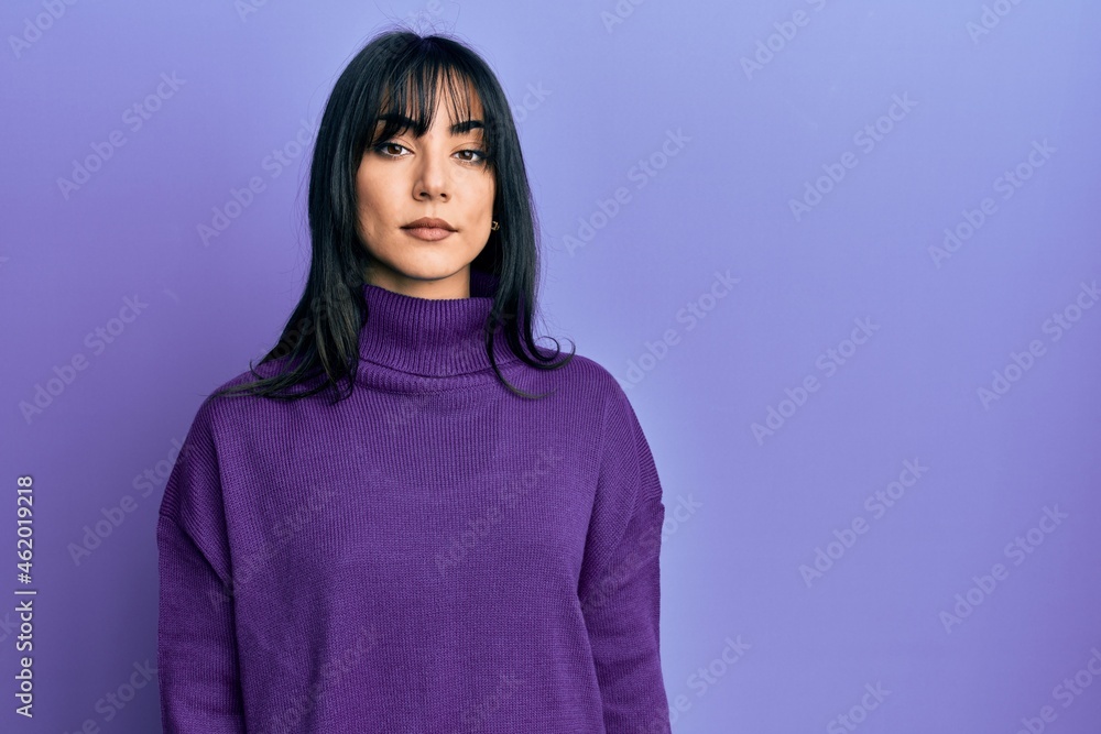 Young brunette woman with bangs wearing turtleneck sweater relaxed with serious expression on face. simple and natural looking at the camera. Young brunette woman with bangs wearing turtleneck sweater relaxed with serious expression on face. simple and natural looking at the camera.
