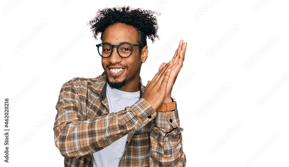 Young african american man with beard wearing casual clothes and glasses clapping and applauding happy and joyful, smiling proud hands together Young african american man with beard wearing casual clothes and glasses clapping and applauding happy and joyful, smiling proud hands together
