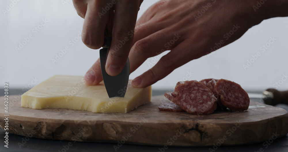 man cutting vintage cheese on olive board