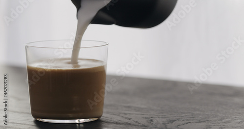 making cappuccino in tumbler glass on black aok table photo