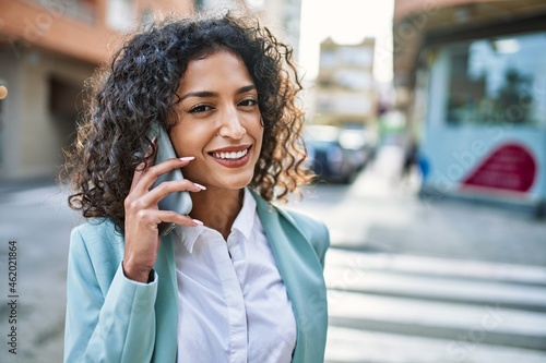 Young hispanic business woman wearing professional look smiling confident at the city speaking on the phone