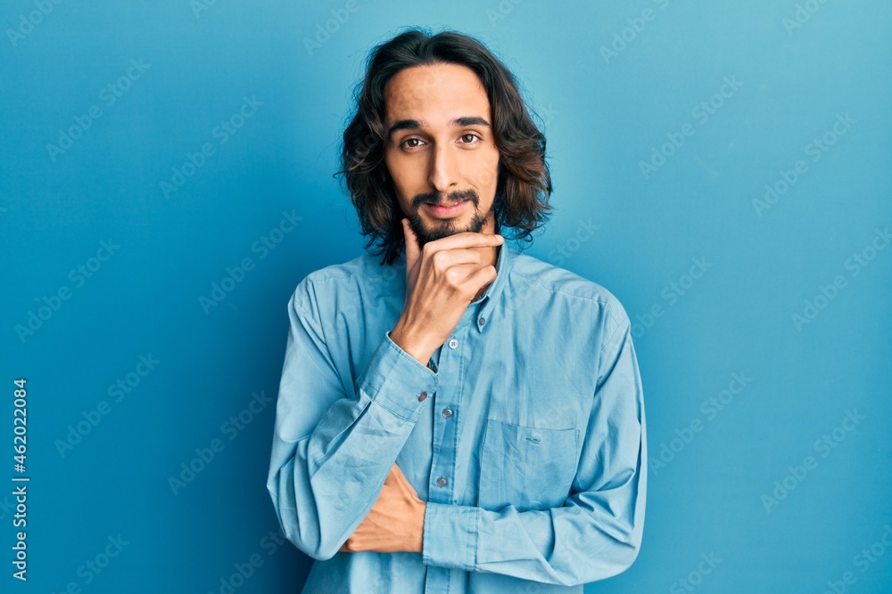 Young hispanic man wearing casual clothes with hand on chin thinking about question, pensive expression. smiling with thoughtful face. doubt concept.