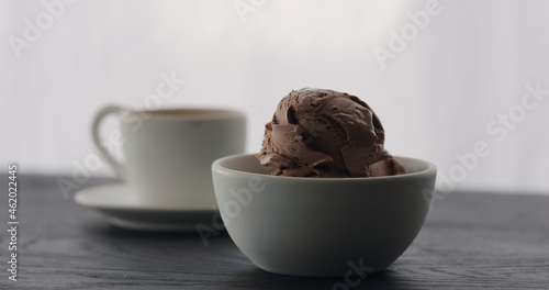 chocolate ice cream into white bowl with espresso on black wood table
