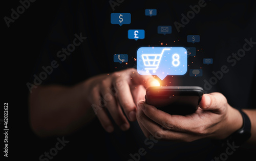 Businessman holding smartphone with shopping trolley cart to input new order for online shopping concept.