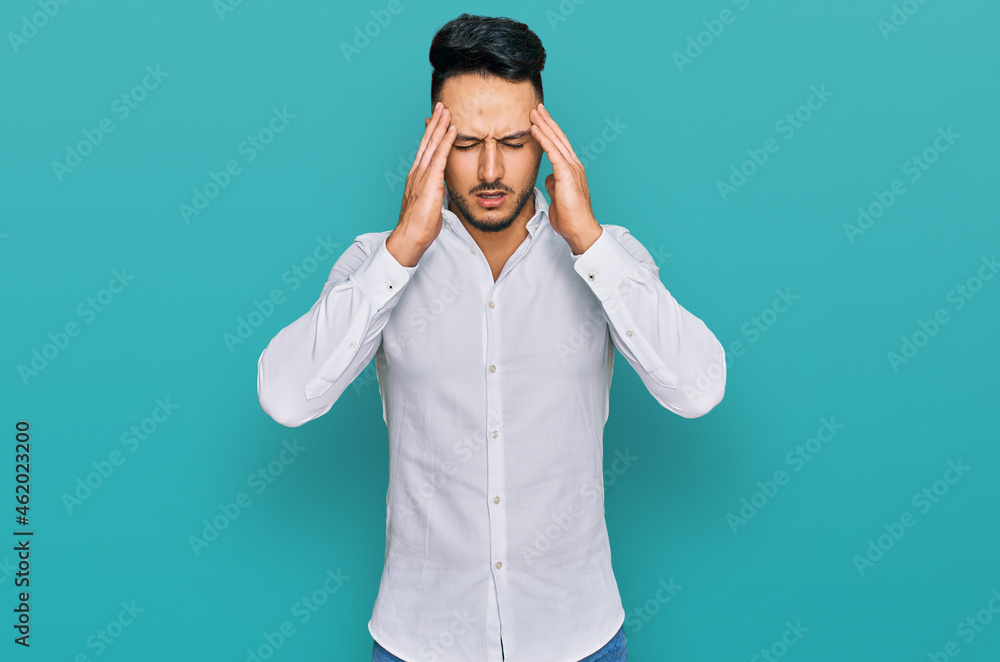 Young arab man wearing casual clothes with hand on head for pain in head because stress. suffering migraine. Young arab man wearing casual clothes with hand on head for pain in head because stress. suffering migraine.
