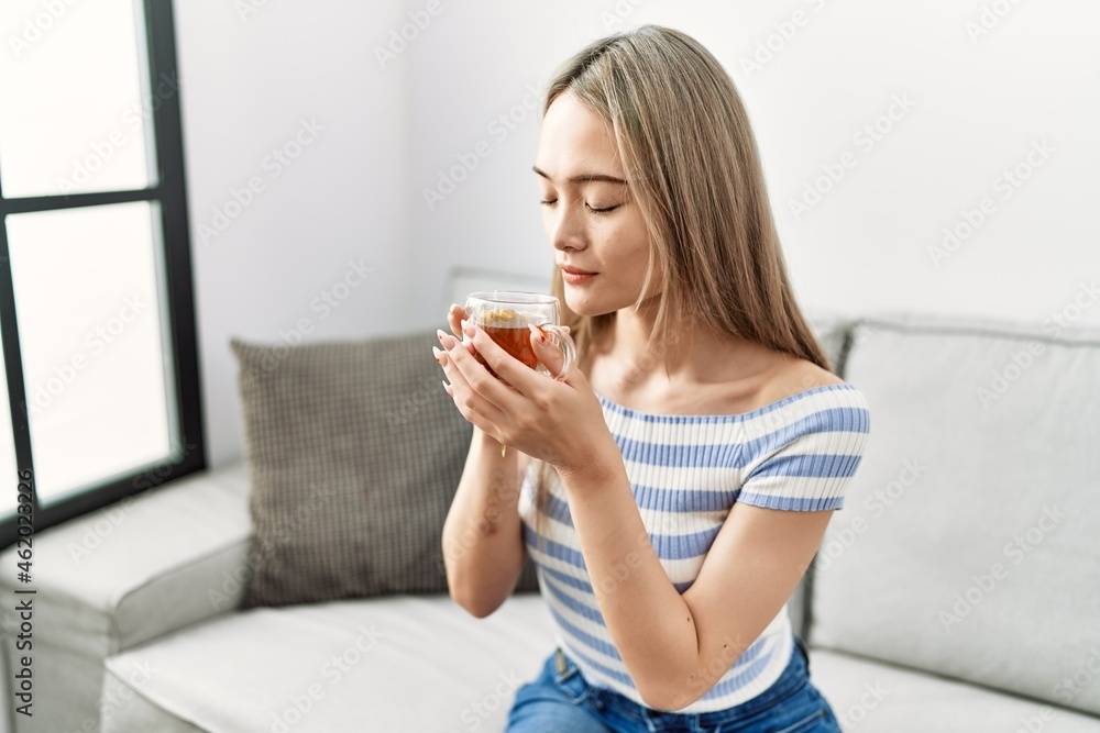 Young chinese woman smiling confident drinking tea at home