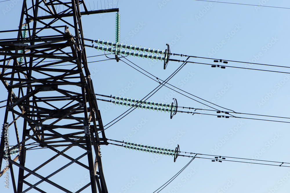 power line construction of cable supports and insulators. High voltage power line on blue sky background in Sunny day. Close-up. industry, iron construction, high voltage pole power line construction of cable supports and insulators. High voltage power line on blue sky background in Sunny day. Close-up. industry, iron construction, high voltage pole