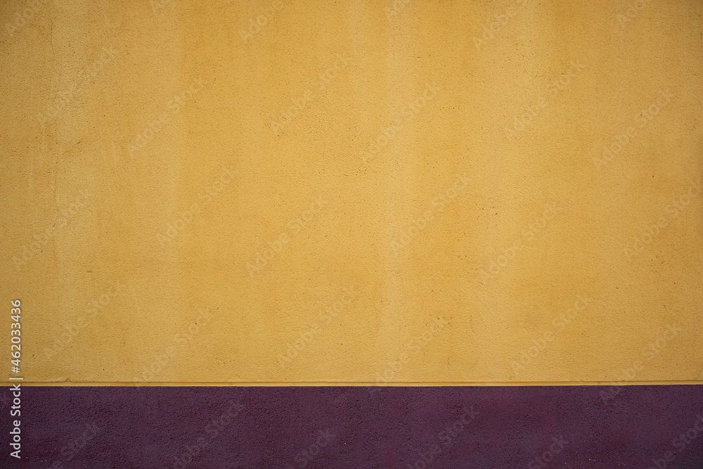 Yellow plaster wall with purple baseboard