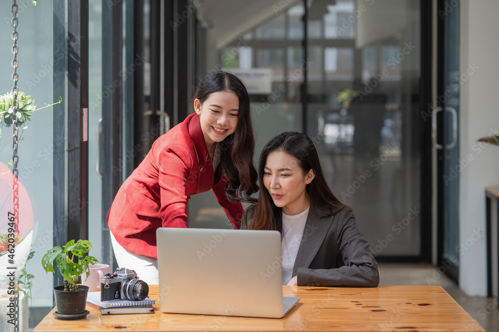 Two casual Asian businesswomen discussing work in the office Two casual Asian businesswomen discussing work in the office