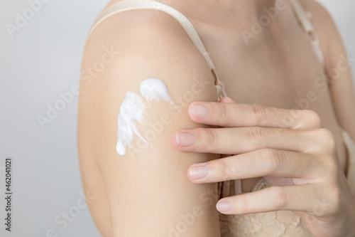 woman applying cream on her upper arm