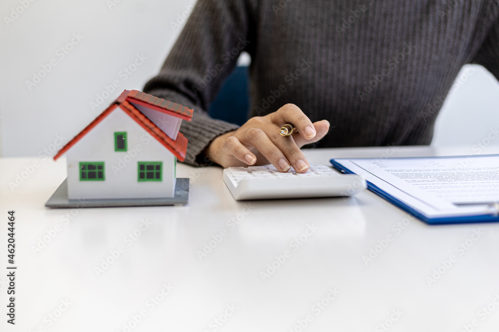 Fototapeta premium Businessman presses a calculator to calculate the amount on a housing estate sales document, he is meeting with the sales manager to place a sale and make promotions, marketing plans to increase sales