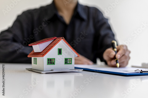 Small house model placed on the desk, business people attend meetings with sales managers to place sales and promotions, marketing plans to generate more sales. Sales management concept.