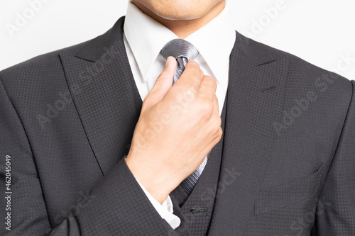 白背景の前に立ってスーツを着る男性ビジネスマン