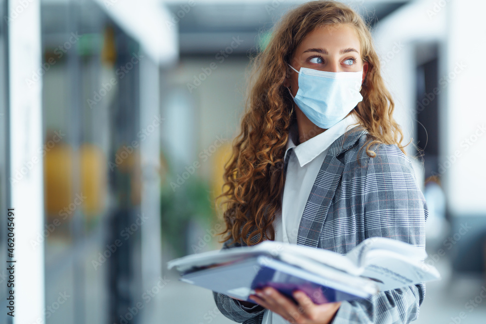 Portrait of young business woman in protective face mask at office. Female Entrepreneur. People, business, freelance, work concept. COVID - 19. Portrait of young business woman in protective face mask at office. Female Entrepreneur. People, business, freelance, work concept. COVID - 19.