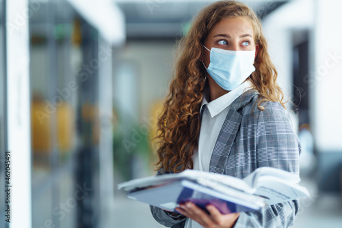 Portrait of young business woman in protective face mask at office. Female Entrepreneur. People, business, freelance, work concept. COVID - 19.