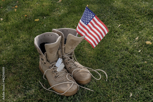 Boots of an American soldier who returned home as a symbol of a hero with an American flag waving in the wind